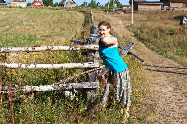 Young woman villager standing in front of wooden fence — Stock Photo, Image