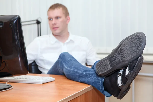 Przystojny młody biznesmen odpoczynku z nogi na biurko — Zdjęcie stockowe