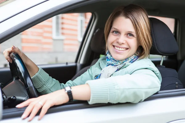 Autista donna seduta in macchina, sorridente e con il volante in mano — Foto Stock