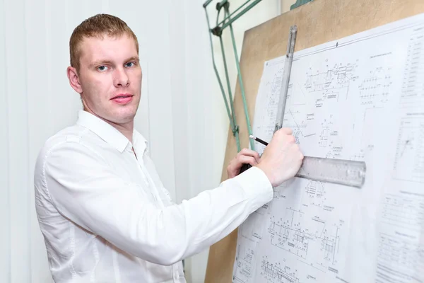 Engineer with blueprint standing near old drawing board — Stock Photo, Image