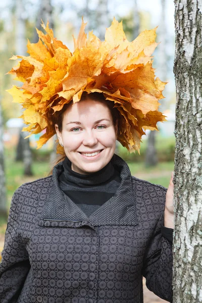 バーチの木の近くにカエデ花輪立って魅力的な若い女性 — ストック写真