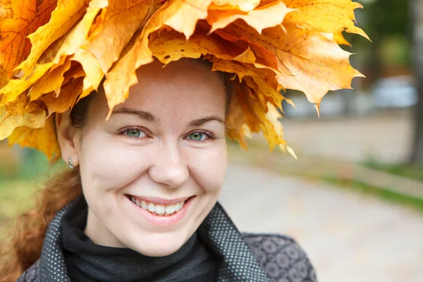 Lachende vrouw gezicht met gele esdoorns krans — Stockfoto