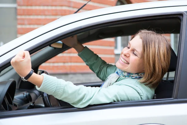 Ung blond kvinna skakar hennes knytnäve i bil — Stockfoto