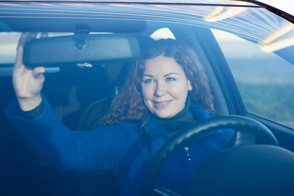 Mulher bonita no carro se preparando para dirigir corrigindo espelho traseiro — Fotografia de Stock