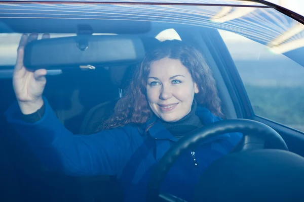 Hübsche Frau im Auto bereitet sich auf Korrektur des Rückspiegels vor — Stockfoto