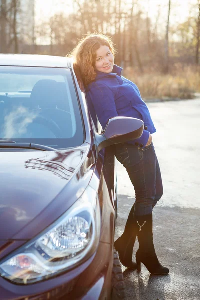 Joyful woman in full length leaned against car — Stock Photo, Image