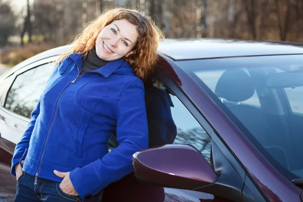 Beautiful woman leaned to car smiling and looking at camera — Stock Photo, Image