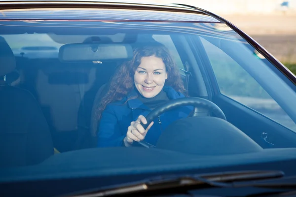 Привлекательный водитель внутри автомобиля улыбается через лобовое стекло — стоковое фото