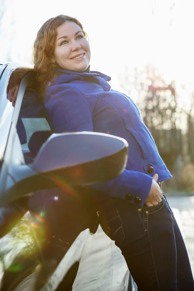 Attractive girl leaned against car standing in sun lights — Stock Photo, Image