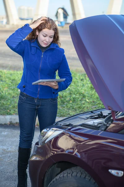 Mujer en el pensamiento de pie cerca de un coche con tablet pc —  Fotos de Stock