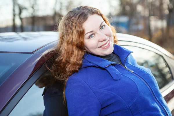 Donna capelli ricci gioiosa appoggiato contro auto e sorridente — Foto Stock