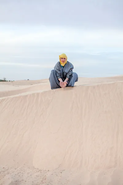 Caucasian person in protection eastern clothes pouring sand by hands on desert dune — Stock Photo, Image