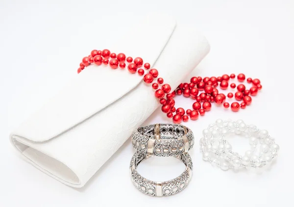 Золотые браслеты, красное ожерелье с кошельком на белом фоне — стоковое фото