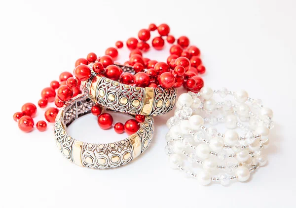 Two white gold braceletes and red necklace on white background — Stock Photo, Image