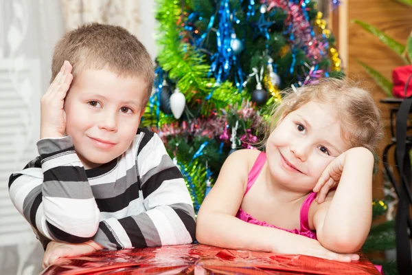 Hermano y hermana con regalos sentados cerca del árbol de Navidad —  Fotos de Stock