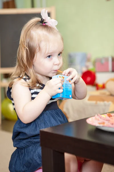 Lindo niño pequeño sentado en la mesa en la habitación doméstica —  Fotos de Stock