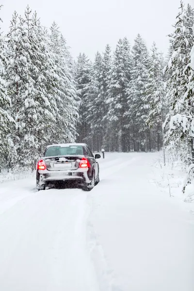 Αυτοκίνητο οδήγησης σε έναν επαρχιακό δρόμο στο χειμερινό δάσος — Φωτογραφία Αρχείου
