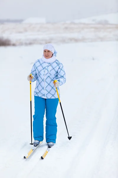 Mulher caucasiana feliz esquiando no campo de inverno sozinho — Fotografia de Stock