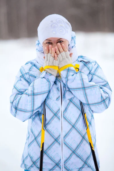 Kaukasische vrouw skiër opwarming van de aarde bevroren handen met langlauf stokken in de winter — Stockfoto