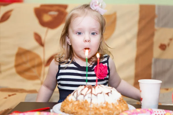 Маленькая белая девочка с двумя ушами, задувающими свечи на торте. — стоковое фото