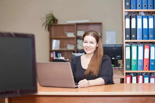 Mujer caucásica de belleza en interior de la oficina con el portátil en el escritorio — Stok fotoğraf