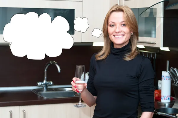 Счастливая улыбающаяся женщина в кухонном интерьере пьет шампанское — стоковое фото