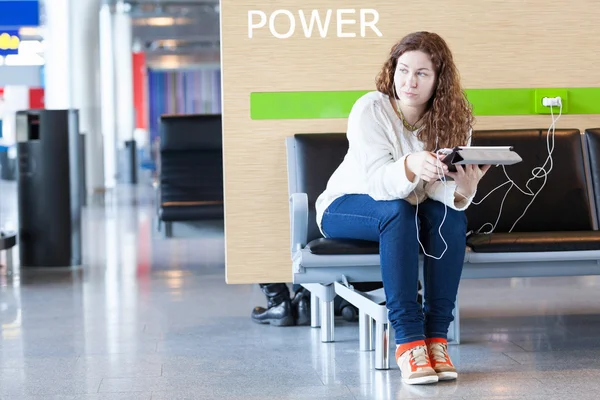 Nachdenkliche Frau mit elektronischen Geräten in der Nähe, um Ihr Handy aufzuladen — Stockfoto