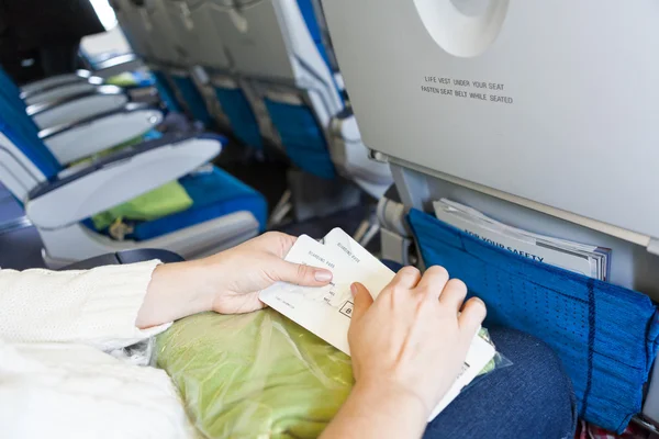 Kaukasierin sitzt mit Bordkarte in der Hand im Flugzeug — Stockfoto