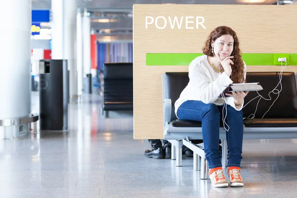 Frau mit elektronischen Geräten in der Nähe des Ladeortes für ihr Handy — Stockfoto