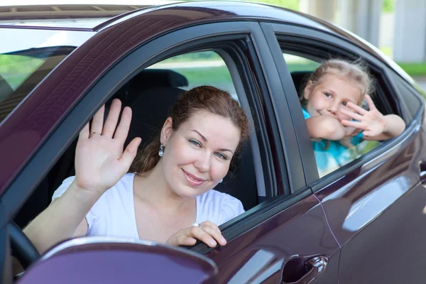 Happy Caucasians mother and young daughter waving from car windows — Stock Photo, Image