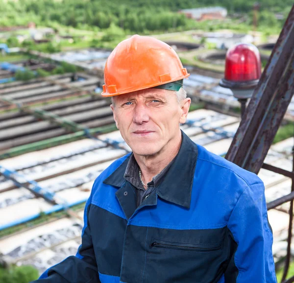 Portret van senior Kaukasische arbeider permanent tegen waterzuiveringsinstallatie — Stockfoto