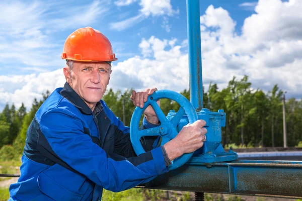 Portrait of an senior Caucasian man in a working uniform with pipe valve — Stock Photo, Image