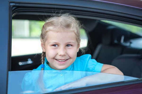 Šťastný bělochů holčička při pohledu z okna auta — Stock fotografie