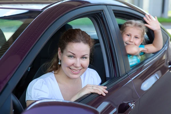 Glückliche Kaukasier Mutter und kleine Tochter blicken aus Autofenstern in die Kamera — Stockfoto