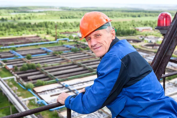 Кавказький зрілих ручний працівник в синій уніформи й апельсиновий hardhat Озираючись назад — стокове фото