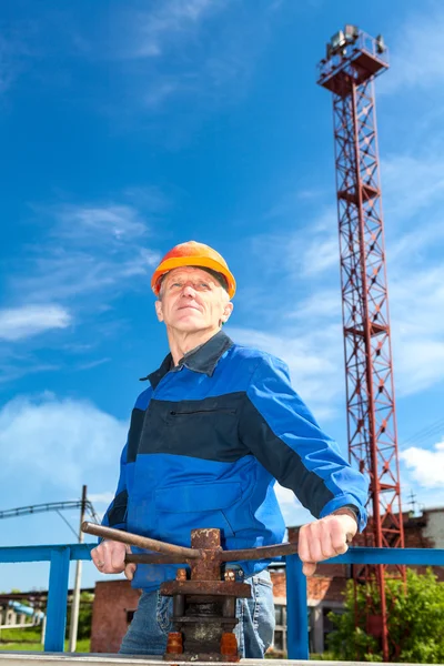 Senior Caucasian man in a working uniform with pipe valve. Looking fare away — Foto Stock