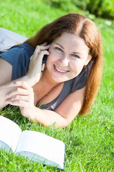 Молодая женщина с книгой говорит по телефону — стоковое фото