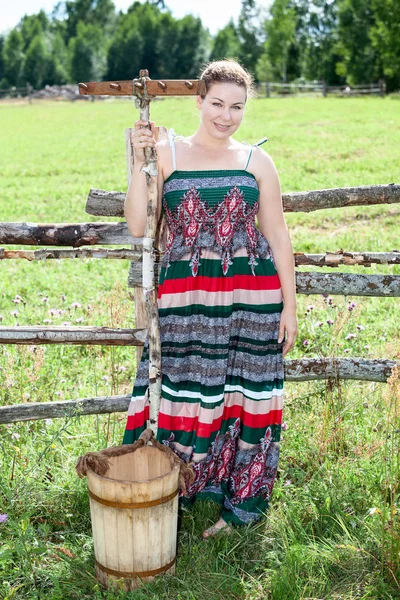 Pretty countrywoman with wooden rake and bucket — Stock Photo, Image