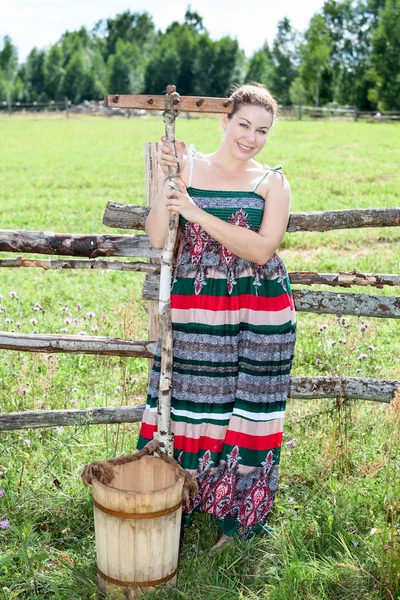 Bella bruna con rastrello e secchio in un campo — Foto Stock