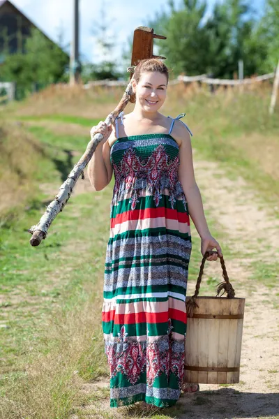 Ganska ung byn kvinna med trä rake och hink — Stockfoto