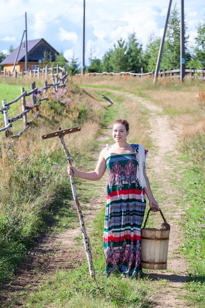 Countrywoman standing with rakes — Stock Photo, Image