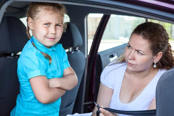 Caucasian girl does not want fastening in child safety seat in car — Stock Photo, Image