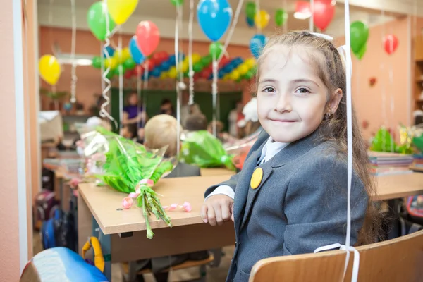 Liten skolflicka sitter vid skrivbord i skolan — Stockfoto