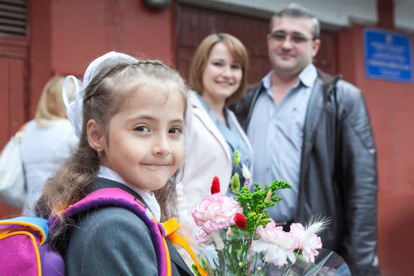 Pequeña colegiala con sus padres en la escuela — Foto de Stock