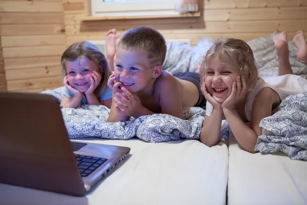 Niños mirando el portátil en la cama —  Fotos de Stock