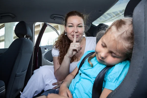 Mother with shh gesture when daughter asleep in car safety seat — Stock Photo, Image