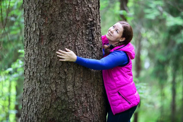 Vrolijke vrouw omhelst pine stam — Stockfoto