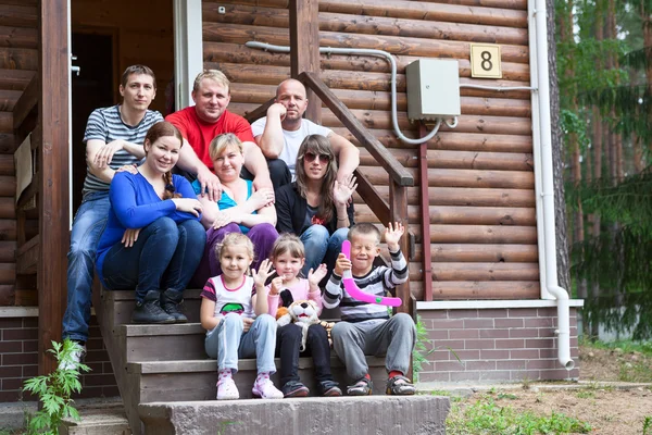 Gran familia caucásica con tres hombres, cuatro mujeres y tres niños sentados en el porche de la casa — Foto de Stock