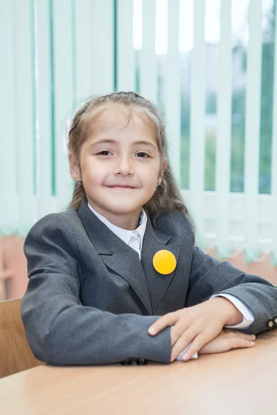 Μικρή μαθήτρια που κάθεται στο γραφείο και στο σχολείο — Φωτογραφία Αρχείου