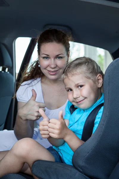 Mother and child with thumb up gesture in car safety seat — Stock Photo, Image